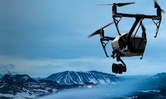 A drone captures an aerial view of a road with majestic mountains in the background
