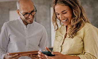 A smiling man and woman looking at a tablet together.