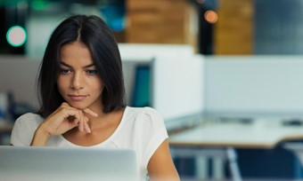 A woman sat at her computer with her hand on her chin