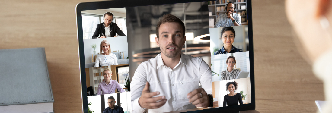 A person using a laptop to video conference with a group of people displayed on the screen.