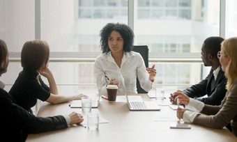 A woman speaks to her colleagues at a conference table