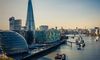 A panoramic view of London featuring The Shard tower alongside the River Thames, showcasing the city's skyline.