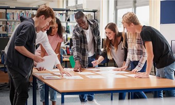 A diverse team of people problem solving around a large wooden table