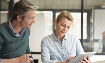 A man and woman examining a tablet computer together