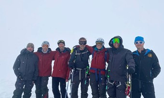 A group of men in arctic expedition gear amidst a snowy white environment